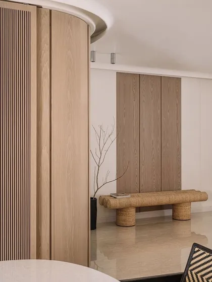 The entrance foyer of Kanso House, featuring a woven bench and minimalist wood paneling. The design is clean and uncluttered, creating a welcoming sense of calm.