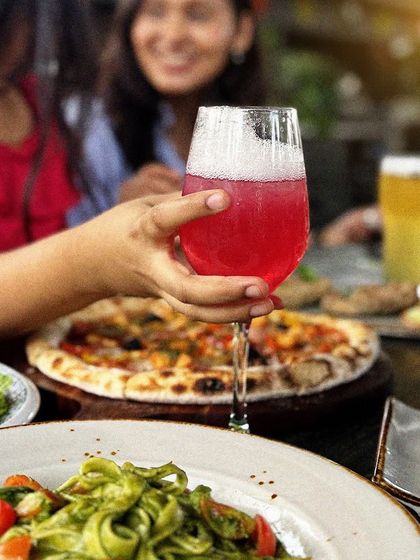 A toast to good company. A colorful cocktail, a fresh craft beer, and a table full of food make for the perfect get-together.