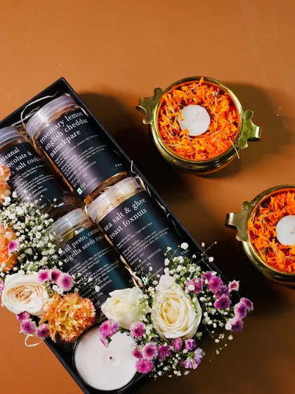 Our Azzi hamper is a celebration of savoury flavours, featuring six jars of our artisanal snacks. This gift box is adorned with fresh flowers and diyas, making it a complete and thoughtful Diwali present.