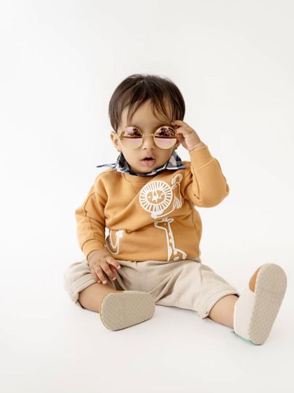 A stylish toddler portrait for a first birthday, showing off his cool sunglasses and casual outfit.