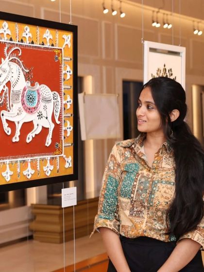 A visitor admiring a traditional horse painting with intricate mirror-work at the 'Aaina' exhibition.