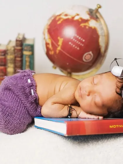 A little scholar theme, with a baby wearing glasses and sleeping on a 'Motivation Diary' next to a globe.