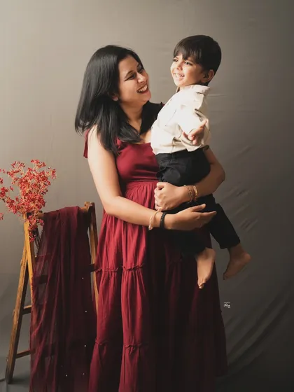 A mother and son sharing a sweet, candid moment. The simple studio setup with a pop of color from the draped fabric adds a lovely artistic touch.