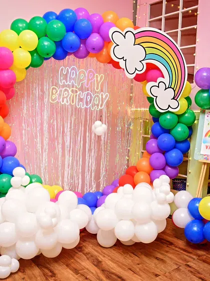 A burst of color with a rainbow-themed birthday party. The circular balloon arch creates a perfect rainbow, complete with fluffy white balloon clouds.