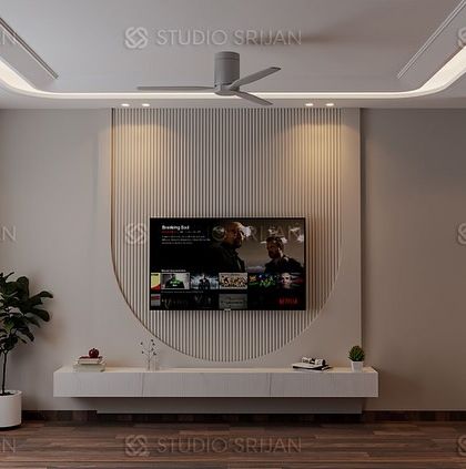 A minimalist bedroom design in Model Town, with a clean, white TV wall featuring a large, curved decorative element. The wooden flooring adds warmth to the space.