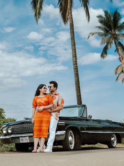 A classic couple portrait with a vintage convertible under tall palm trees. This photo perfectly captures the fun and stylish vibe of a Goa pre-wedding shoot.