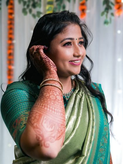 A candid portrait of a bride, highlighting her beautiful smile and the intricate mehendi on her arm.