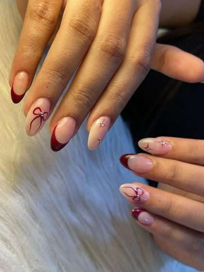 This elegant design is perfect for the festive season. It features a deep red French tip on an almond-shaped nail, with delicate, hand-painted red bows and tiny star accents for a touch of sparkle.