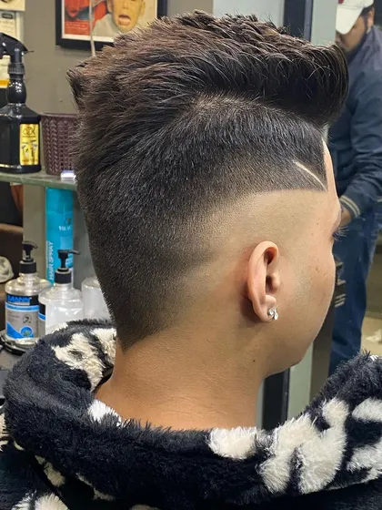 Side view of a high fade with a spiky top, detailed with a single sharp line to accentuate the fade's transition.
