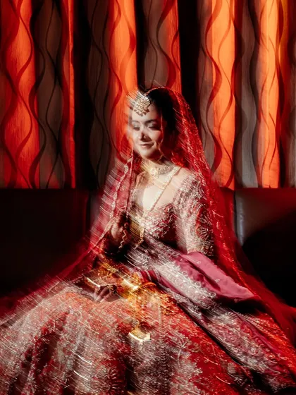 An artistic, motion-blur portrait of the bride, creating a dreamy and ethereal effect with the vibrant red of her lehenga.