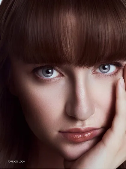 A classic beauty pose, with the model's hand framing her face. This shot is all about creating a connection through the eyes, with soft light that flatters the skin.