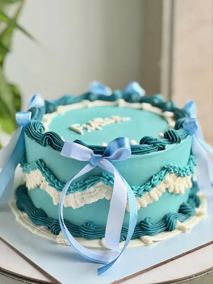 A closer look at the side details of the vintage blue cake, showcasing the layered piping and the elegant way the dual-toned ribbons are tied.