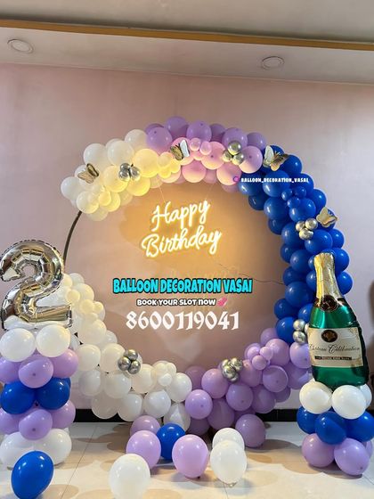 A 2nd birthday party with a unique color combination. The blue, purple, and white balloons on a ring frame are paired with a champagne bottle prop.