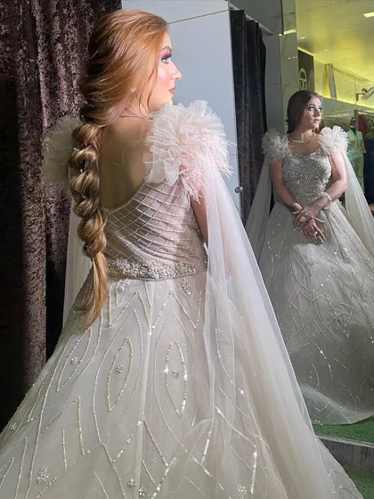 A profile shot of our beige ball gown, showing off the beautiful braided hairstyle and the way the cape sleeves drape over the back. The mirror reflection adds another layer of glamour.
