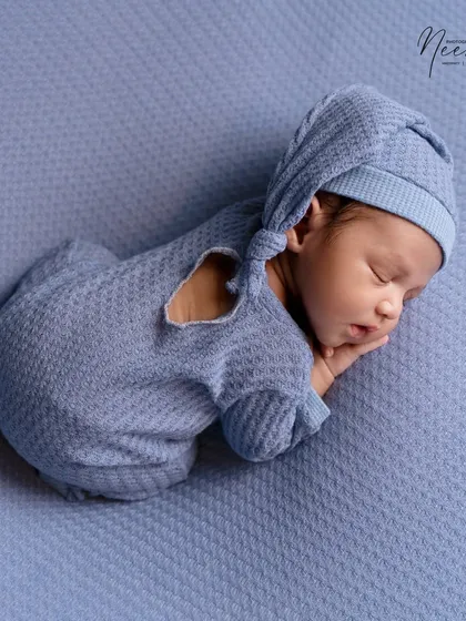 The 'tushy up' pose is perfect for showing the sweet, curled-up nature of a newborn. This little heart cutout on the outfit adds an extra touch of love.