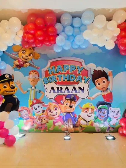 A full view of our Paw Patrol themed birthday backdrop. The setup includes a large banner with all the characters, a colorful balloon arch, and a light up marquee number '5'.