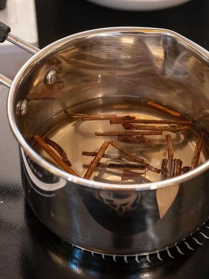 Sappanwood steeping in water on an induction cooktop. This is a key step in the ink extraction process, where we gently heat the botanicals to release their vibrant natural colors.