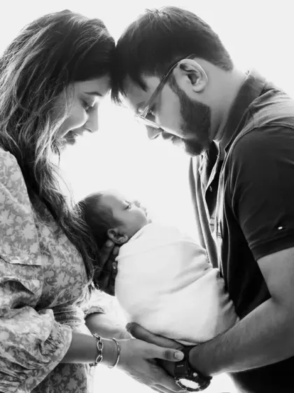 A classic family portrait in black and white. This artistic choice highlights the intimate, loving gaze between the new parents and their baby.
