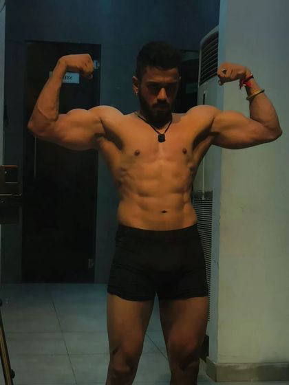 Strong core, strong life. This bicep pose shows a complete physique with a tight midsection and muscular arms.