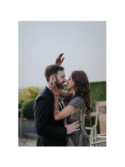A sweet and intimate moment between a couple, with her henna-adorned hand gently touching his face. This close-up shot beautifully blends cultural tradition with modern romance.
