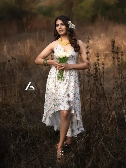 Here is another full-length shot that showcases the model holding flowers. The composition balances the subject with the natural surroundings, creating a beautiful and classic outdoor fashion portrait.