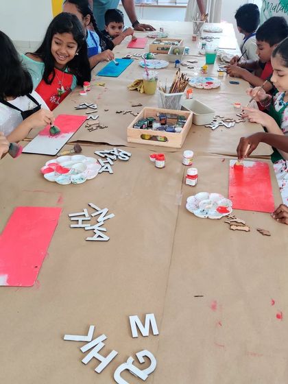 A table full of busy artists! Kids are deeply engaged in painting and decorating their own nameplates during a birthday party.