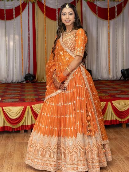 This bright orange lehenga is a stunning choice for a wedding guest. The intricate silver work creates a beautiful pattern that catches the light, making you shine at any celebration.