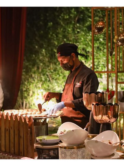 A chef at a live kebab station, set against an elegant, modern backdrop. The setup with scalloped copper bowls and wooden accents shows our commitment to making our cooking stations as aesthetically pleasing as they are delicious.