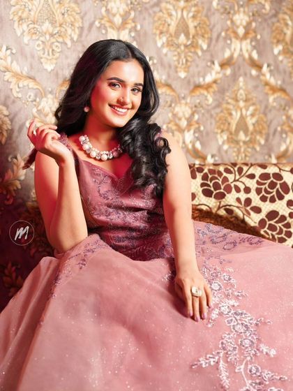 A relaxed and elegant seated pose. The makeup looks flawless and natural.