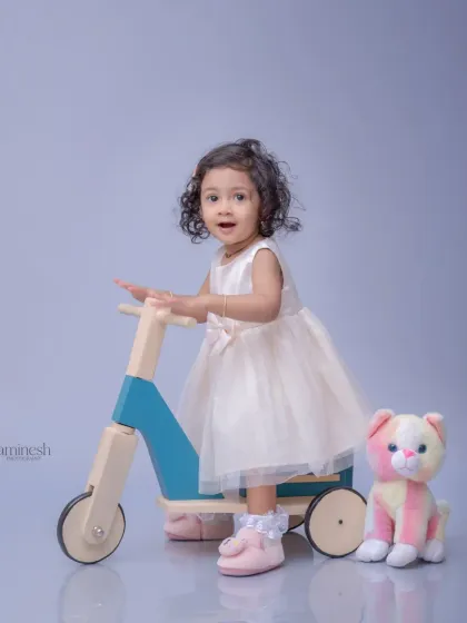 An expressive portrait of a little girl on her toy scooter. Her wide-eyed look and slight smile create an engaging and memorable image.