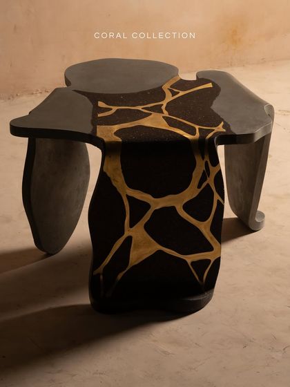 This view of the Coral Collection table showcases its unique, irregular shape. The deep black surface creates a sense of depth, while the golden accents catch the light, adding warmth and sophistication.