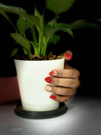 A beautifully composed shot of a festive red and gold nail design.