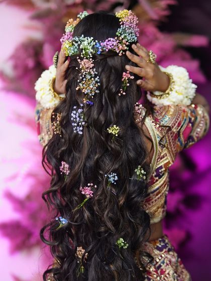 A stunning shot of the back, showcasing the intricate floral hairstyle. For Mehndi and Haldi, a beautiful braid or open curls with flowers is always a great choice.