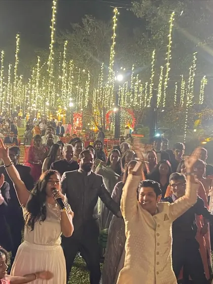 A shot of me leading the crowd in a dance at an outdoor wedding reception under a canopy of fairy lights.