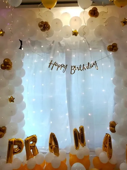 A closer view of the white and gold personalized balloon arch, showing the detail of the star-shaped foil accents.