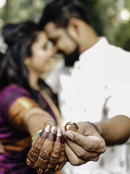 A classic engagement photo, focusing on the rings held by the couple, with their faces blurred in a loving embrace.