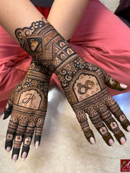 A unique take on engagement mehendi, this design includes the couple's initial 'JR', interlocking rings, and a portrait of the groom.