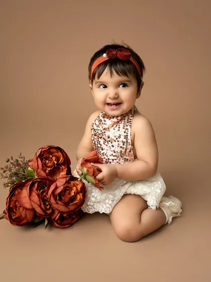 A sweet, curious expression from the birthday girl. The warm, neutral tones of this studio setup create a timeless and elegant first birthday portrait.