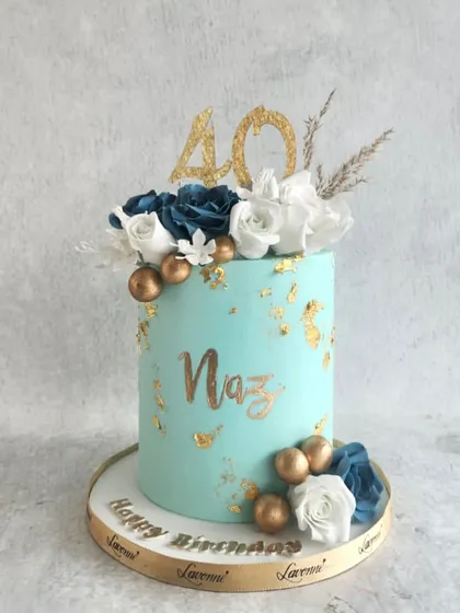 A beautiful cake for a 40th birthday. The teal buttercream is accented with gold leaf and a floral arrangement of white and blue roses.