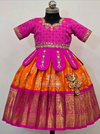 A vibrant combination of pink and orange. The blouse has a unique grid pattern and is paired with a petal-style peplum over a bright orange Banarasi skirt.