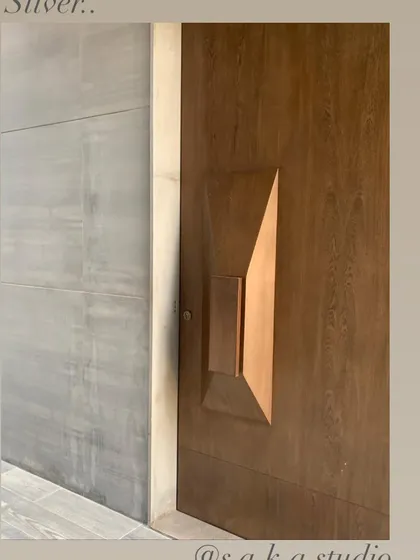 A detail of a custom wooden door with a faceted, sculptural handle. This is an example of how even functional elements can be treated as art, adding a unique and sensory quality to the home.