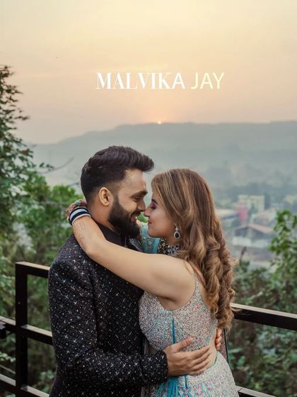 A romantic portrait of the couple during their engagement or Sangeet, set against a backdrop of hills at sunset. Their close embrace and happy smiles perfectly capture the love between them.