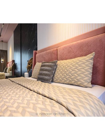 A close-up of the pink upholstered bed in the 'Atmosphere' master bedroom. The geometric pattern on the bedding complements the textures of the headboard and wall panels.
