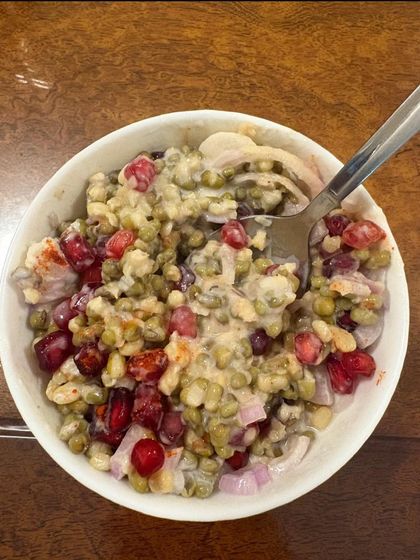A colorful and nutritious moong sprout salad with pomegranate seeds and onions. This is a great option for a light lunch or snack.