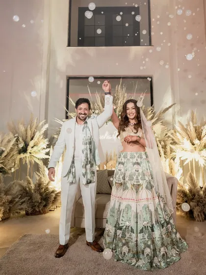 The couple celebrating their union with a bubble-filled moment of joy. The pampas grass decor in the background adds to the dreamy, boho vibe.
