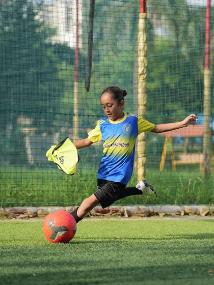 We do not coach who they are. We coach who they will become. A young girl practices her shooting.