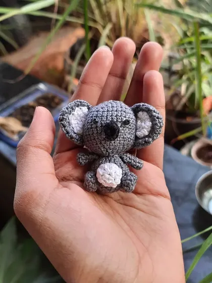The tiny koala amigurumi sitting in my palm. It shows just how small and precious these handmade creations are.