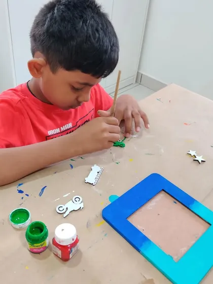 A young boy carefully painting a photo frame for his dad's birthday. Handmade gifts are always the most special.