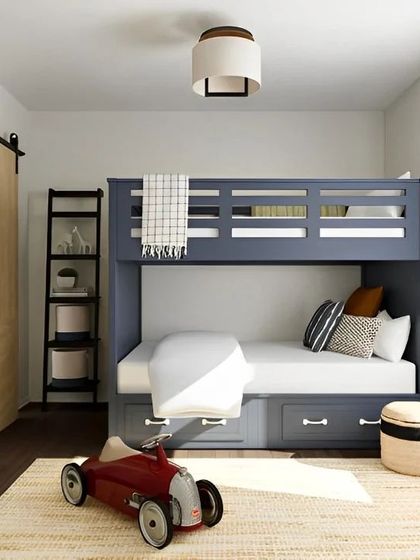 A classic and clean design for a kid's room, featuring a sturdy wooden bunk bed with large storage drawers underneath. The sliding barn door adds a rustic touch while saving space.