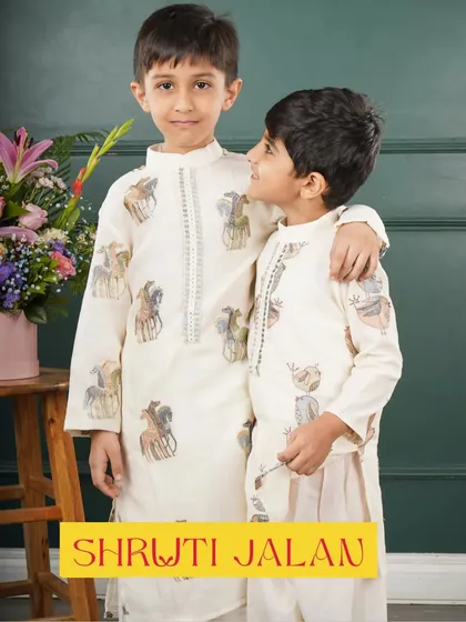 Two brothers sharing a hug in their matching off-white kurtas with a playful potli print. It's a subtle and stylish way for brothers to coordinate.